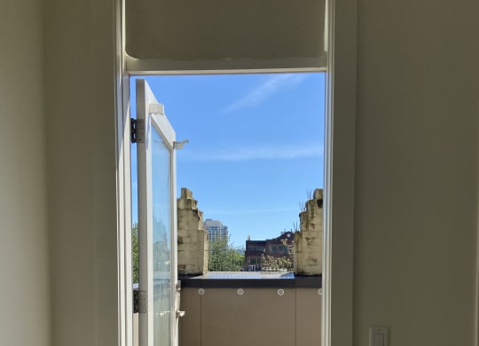 an open window with a view of a building in the distance