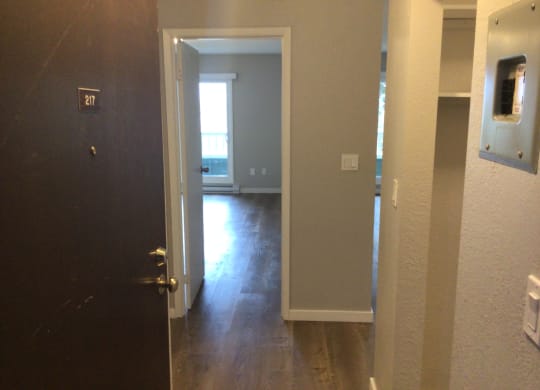 an open door leading to a hallway with a door open and a window in the background
