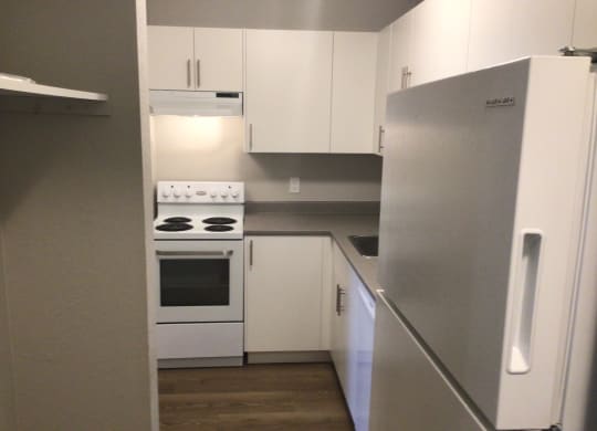 a small kitchen with white cabinets and a white stove