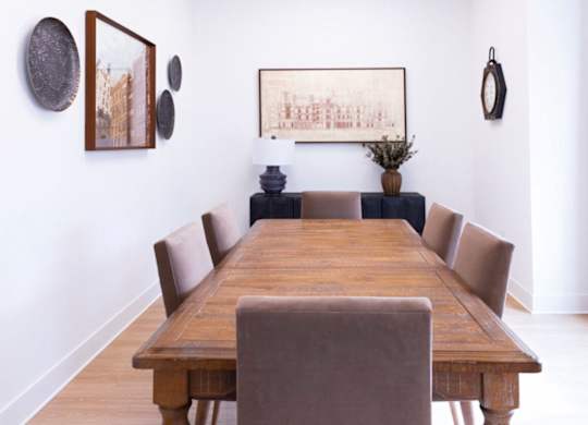 A long wooden table with chairs and pictures on the wall.