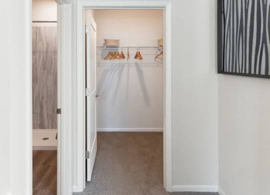 A white closet with clothes hanging on a rack.