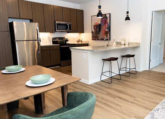 A kitchen with a refrigerator, microwave, and a dining table with chairs.
