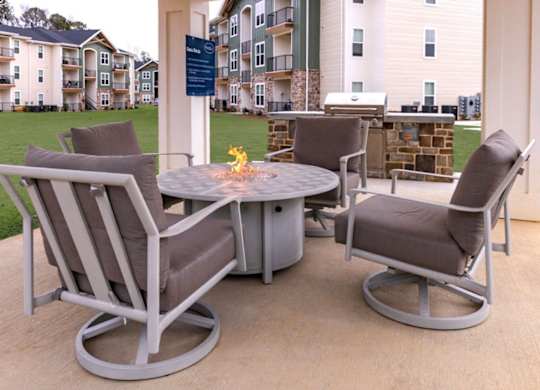 A patio with a table and chairs and a sign in the background.