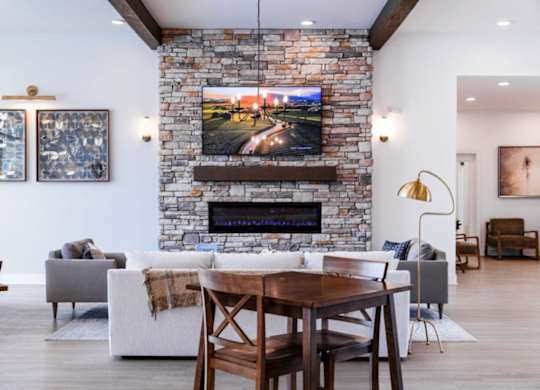 A modern living room with a stone fireplace and a television mounted above it.