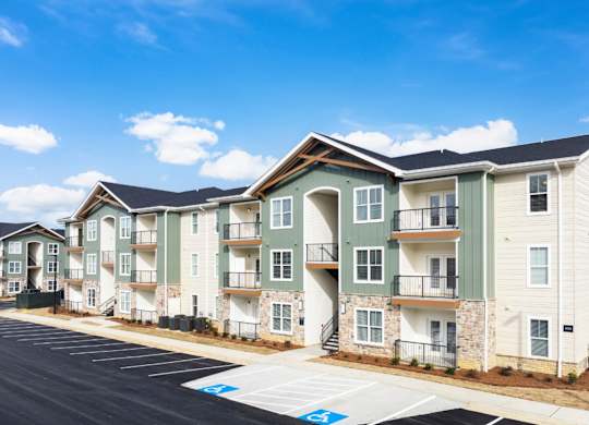 Apartment complex with a parking lot in front.