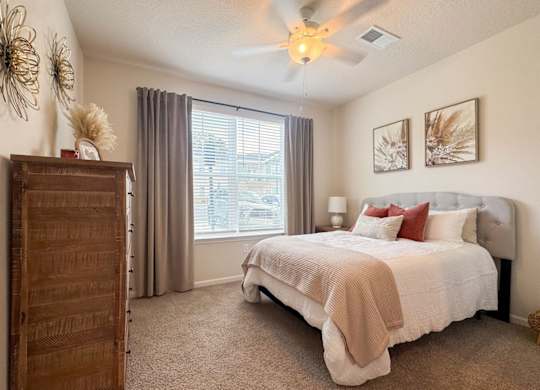 A bedroom with a large bed and a ceiling fan.