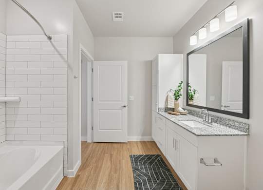 A white bathroom with a white tub and a white sink.at Allegra at Cocoa in Cocoa, FL, 32926