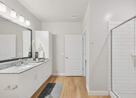 A bathroom with a white tile shower and a white sink.at Allegra at Cocoa in Cocoa, FL, 32926