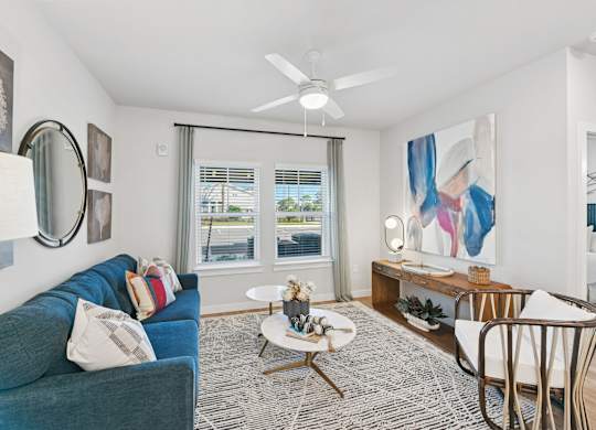 A living room with a blue couch and a white chair.at Allegra at Cocoa in Cocoa, FL, 32926
