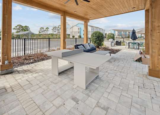 A white table with a black cushion is in the middle of a patio. at Allegra at Cocoa in Cocoa, FL, 32926