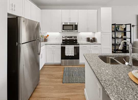 A modern kitchen with a stainless steel refrigerator and a granite countertop. at Allegra at Cocoa in Cocoa, FL, 32926