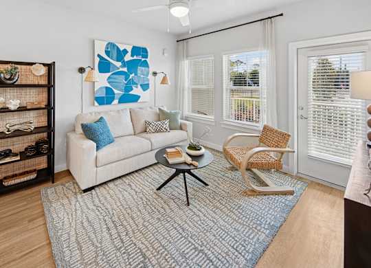 A living room with a white couch, a blue rug, and a wooden shelf. at Allegra at Cocoa in Cocoa, FL, 32926
