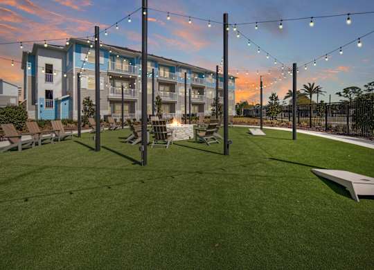 A sunset view of the grassy fire pit area with a Allegra at Cocoa Apartments in the background. at Allegra at Cocoa in Cocoa, FL, 32926