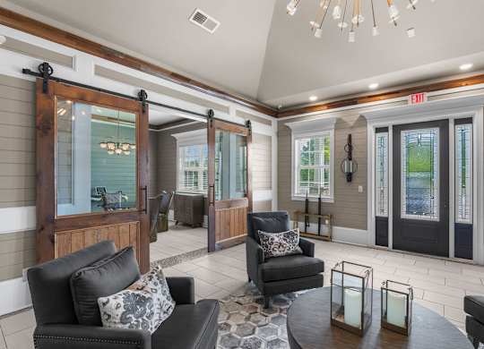 A living room with a black couch and a glass door.  at Mode at Melbourne Apartments, Melbourne, Florida