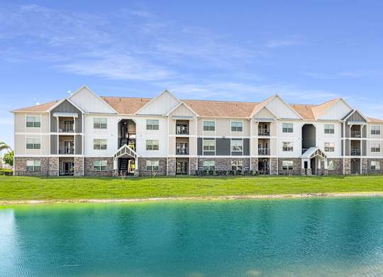 A large building with a lake in front of it at Mode at Melbourne Apartments, Melbourne, Florida