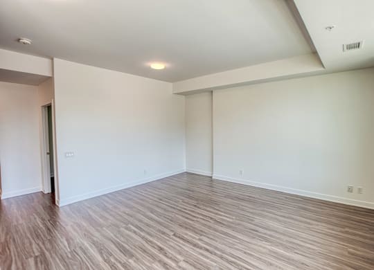 an empty living room with wood flooring and white walls