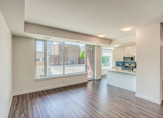 an empty living room and kitchen with a large window