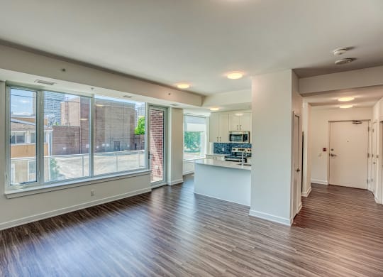 an empty living room with a large window and a kitchen