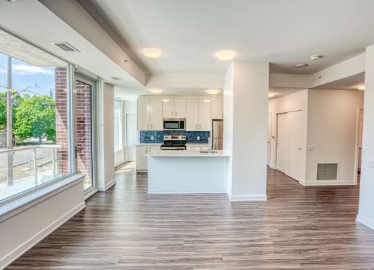 an empty living room and kitchen with a large window