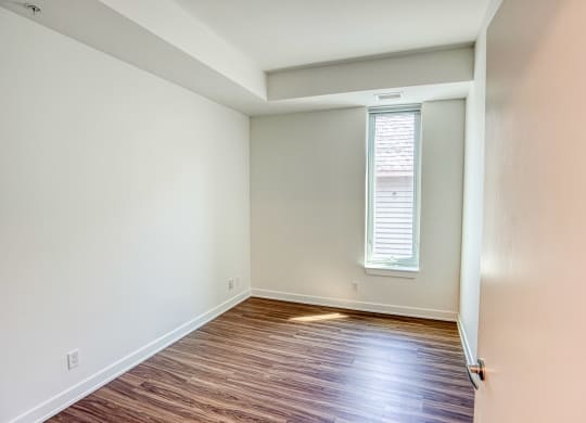 an empty room with wood flooring and a window