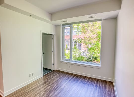 an empty room with a large window and wooden floors