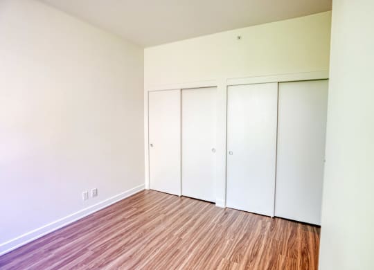 an empty room with wood floors and white closets