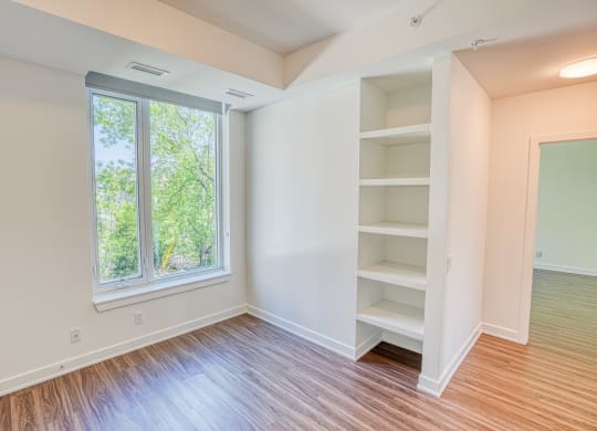 an empty room with wood flooring and a large window