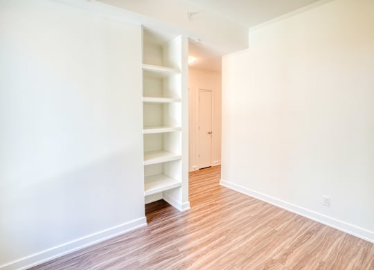an empty room with white shelves and a wood floor