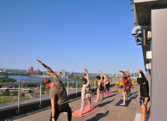 a group of people doing yoga on the roof of a building