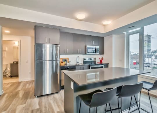 a kitchen with stainless steel appliances and a counter with three chairs