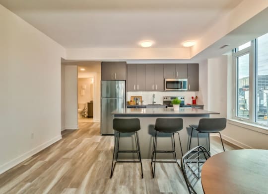 a kitchen with a bar and three stools in front of a large window