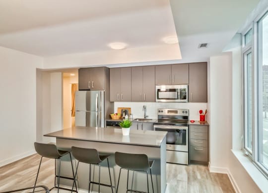modern kitchen with stainless steel appliances and island with three stools