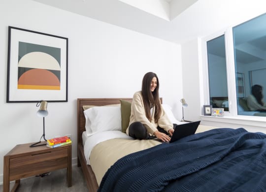 a woman sitting on a bed with a laptop