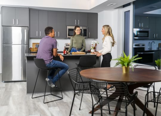 three people in a kitchen with a table