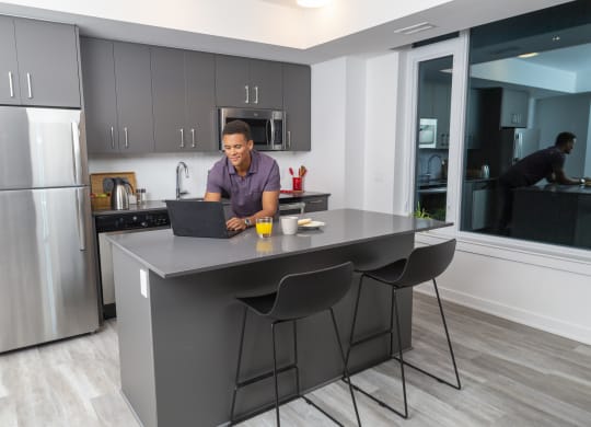 a man sitting at a kitchen counter using a laptop computer