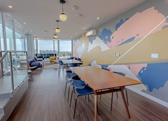 a communal area with tables and chairs and a mural on the wall