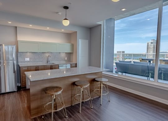a kitchen with a large window and a counter with three stools