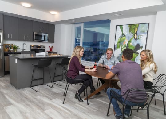 a group of people sitting around a table in a kitchen