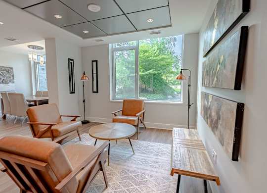 a living room with chairs and tables and a large window