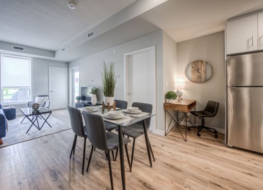 a dining area with a table and chairs and a stainless steel refrigerator
