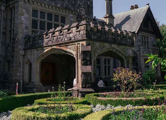 A castle-like building with a flag on top and a garden in front.