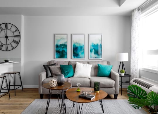 a living room with a gray couch and turquoise pillows