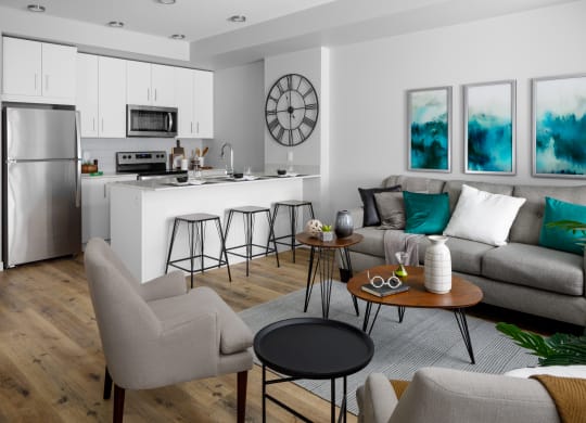 a living room with a kitchen in the background and a couch and chairs in the foreground