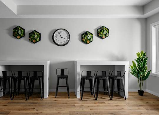 A white table with black chairs and a clock on the wall.
