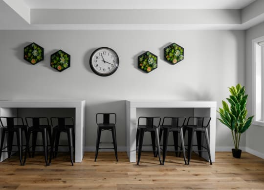two tables and three stools in a room with a clock on the wall