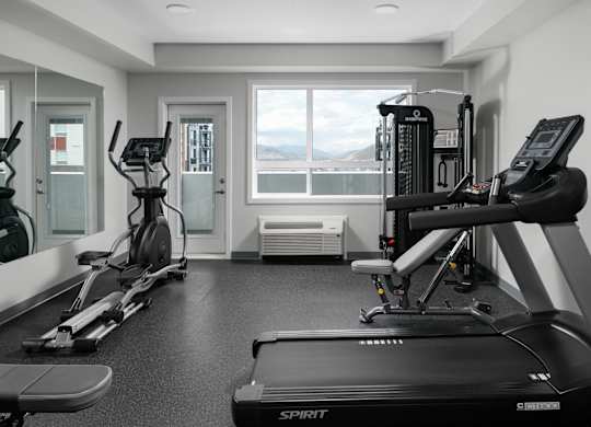 A black and white photo of a gym with a treadmill in the foreground.