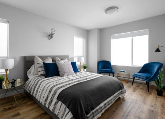 a bedroom with a bed and two blue chairs