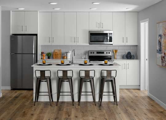 A kitchen with white cabinets and a wooden floor.