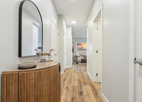 A hallway with a wooden floor and white walls.