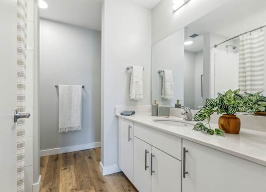A bathroom with white cabinets and a wooden floor.